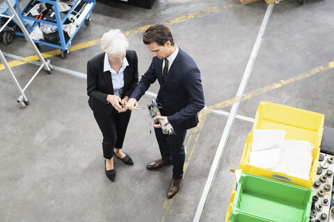Geschäftsmann und ältere Geschäftsfrau prüfen ein Werkstück in einer Fabrik, lizenzfreies Stockfoto