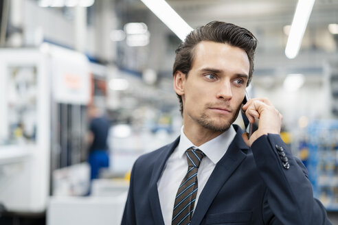 Porträt eines Geschäftsmannes am Handy in einer Fabrik - DIGF05757