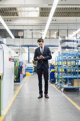 Businessman using cell phone in a factory - DIGF05758