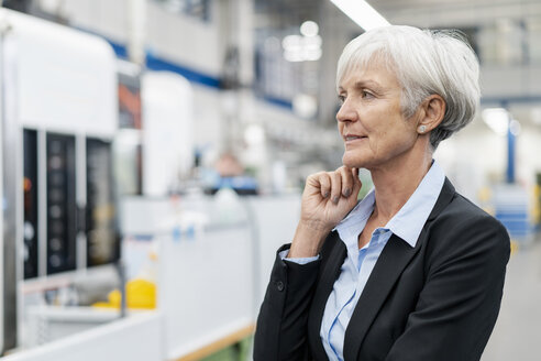 Porträt einer älteren Geschäftsfrau in einer Fabrik, die sich umschaut - DIGF05762
