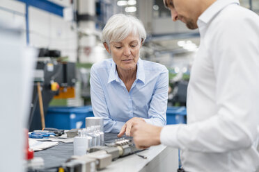 Businessman and senior businesswoman examining workpiece in a factory - DIGF05766