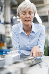 Porträt einer älteren Geschäftsfrau in einer Fabrik mit Blick auf ein Werkstück - DIGF05768