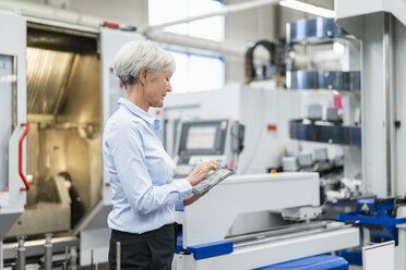 Senior businesswoman using tablet in a factory - DIGF05779