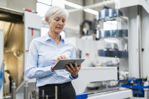 Senior businesswoman using tablet in a factory - DIGF05780