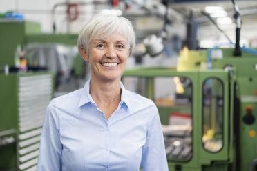 Porträt einer lächelnden älteren Geschäftsfrau in einer Fabrik - DIGF05785