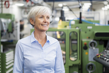 Porträt einer lächelnden älteren Geschäftsfrau in einer Fabrik, die sich umschaut - DIGF05786