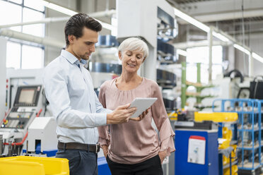 Businessman and senior woman with tablet in a factory - DIGF05799