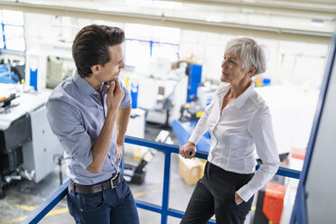 Geschäftsmann und ältere Geschäftsfrau im Gespräch in einer Fabrik - DIGF05812