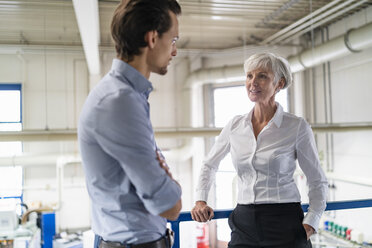 Businessman and senior businesswoman talking in a factory - DIGF05813