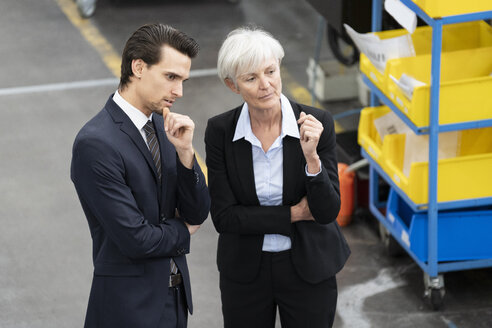 Geschäftsmann und ältere Geschäftsfrau im Gespräch in einer Fabrik - DIGF05819