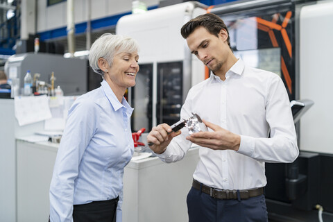 Geschäftsmann und ältere Geschäftsfrau messen ein Werkstück in einer Fabrik, lizenzfreies Stockfoto