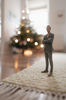 Businessman figurine standing next to a Christmas tree at home - FLAF00150