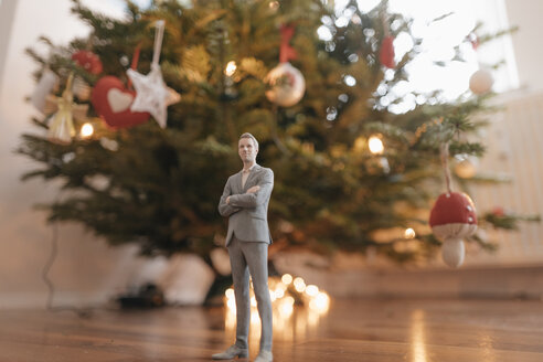 Businessman figurine standing next to a Christmas tree at home - FLAF00152