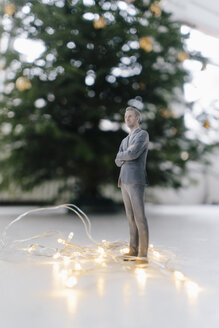 Businessman figurine standing next to a Christmas tree at home - FLAF00158