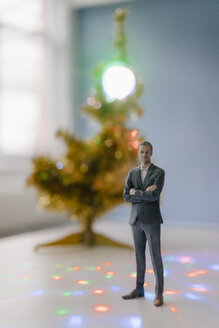 Businessman figurine standing next to a Christmas tree at home - FLAF00159