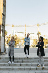 Three serious friends standing on stairs looking sideways - JRFF02645