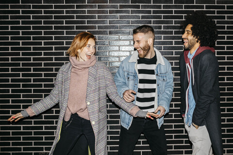 Three happy playful friends at a black wall stock photo