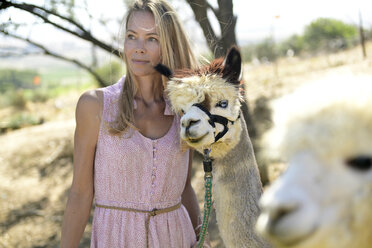 Portrait of blond woman with leashed alpaca - ECPF00499