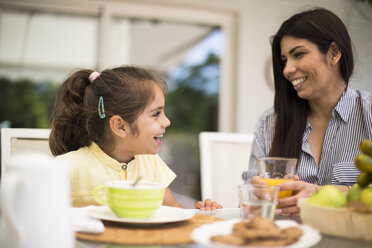 Happy mother and daughter having breakfast at home - ABZF02224