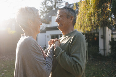 Glückliches zärtliches älteres Paar, das sich im Garten an den Händen hält - KNSF05516