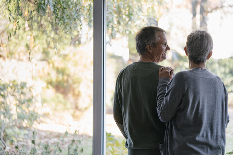 Senior couple standing at panorama window stock photo