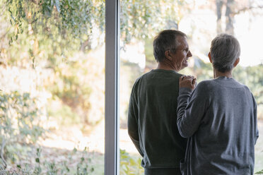 Senior couple standing at panorama window - KNSF05520