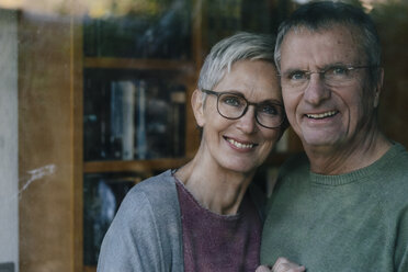 Porträt eines glücklichen älteren Paares hinter einer Fensterscheibe - KNSF05528