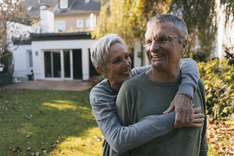 Glückliches zärtliches älteres Paar, das sich im Garten umarmt, lizenzfreies Stockfoto