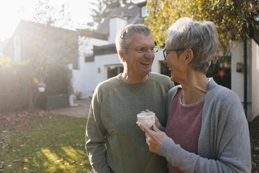 Happy senior couple with cup of coffee in garden - KNSF05568