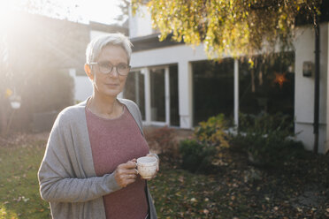 Porträt einer reifen Frau mit einer Tasse Kaffee im Garten - KNSF05569