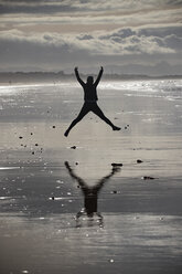 Joggerin springt am Strand - KBF00493