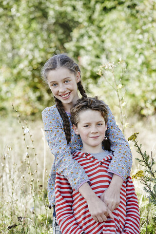 Porträt eines lächelnden Mädchens und eines kleinen Bruders in der Natur, lizenzfreies Stockfoto