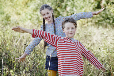 Porträt eines Jungen und seiner älteren Schwester beim Spielen in der Natur - RORF01747