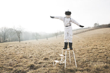 Junge im weißen Raumanzug mit erhobenen Armen auf einer Stufe mit Virtual-Reality-Brille - HMEF00203