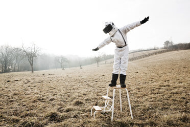 Boy wearing white space suit with raised arms on a step with virtual reality glasses - HMEF00204