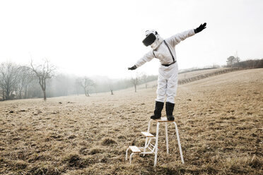Junge im weißen Raumanzug mit erhobenen Armen auf einer Stufe mit Virtual-Reality-Brille - HMEF00204