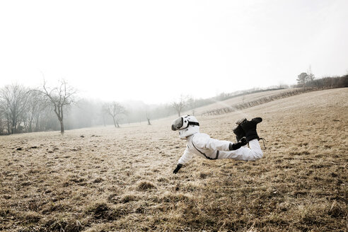 Boy wearing white space suit is posing outdoor on a meadow with virtual reality glasses - HMEF00205