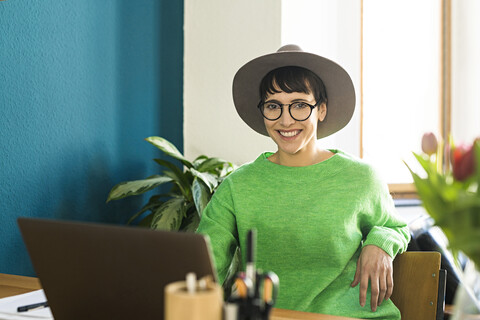 Porträt einer glücklichen Geschäftsfrau im Heimbüro, die an ihrem Laptop arbeitet, lizenzfreies Stockfoto