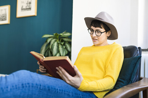Frau entspannt im Liegestuhl und liest ein Buch, lizenzfreies Stockfoto