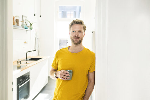 Confident casual man with coffee mug leaning against door case - SBOF01784