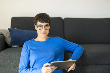 Portrait of casual short-haired woman in living room using a tablet - SBOF01794