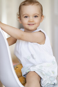 Porträt eines lächelnden Kleinkindes, das auf einem Stuhl sitzt - DIGF05847