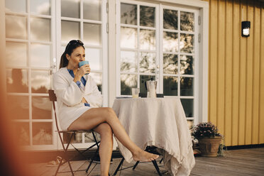 Reife Frau in voller Länge beim Kaffeetrinken auf der Veranda einer Ferienvilla - MASF11072