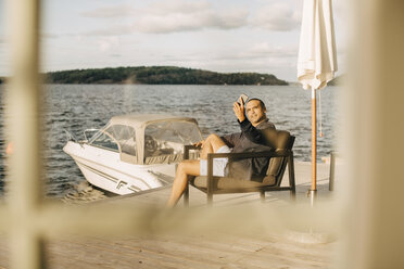 Reifer Mann, der ein Selfie mit seinem Handy macht, während er auf der Terrasse am See sitzt - MASF11076