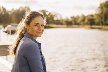 Portrait of smiling mid adult woman by lake during sunny day - MASF11095