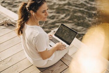 High angle view of mature woman using laptop while sitting at patio - MASF11102