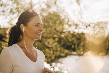 Smiling mature woman talking through headphones in summer vacation - MASF11109