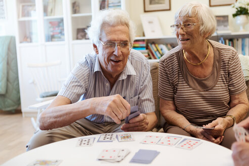 Senior couple playing cards at table in nursing home - MASF11131