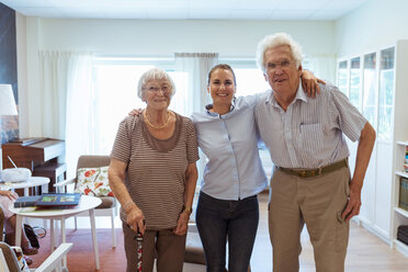 Porträt einer lächelnden jungen Frau mit zusammenstehenden Großeltern in einem Pflegeheim - MASF11136