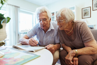 Senior couple doing crossword puzzle in newspaper at nursing home - MASF11141